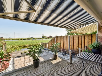 Neat paved patio with sitting area and small garden near wooden fence